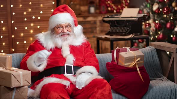 Man in Santa Claus Costume and Cap Posing Waving Hand at Christmas Tree