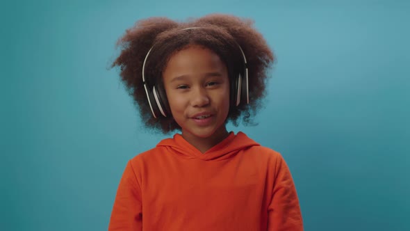 Confident African American girl in wireless headphones talking at camera