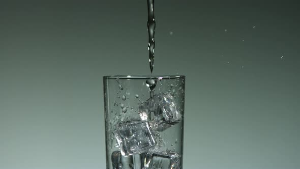 Carbonated liquid pouring into glass filled with ice