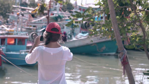 Girl in Cap Shoots Harbor with Asian Fishing Boats Backside