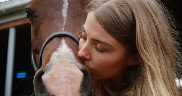 Woman kissing horse in stable 4k