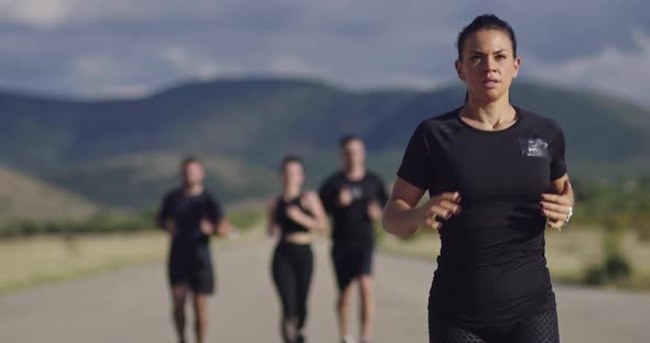 Multiethnic Group of Athletes Running Together on a Panoramic Countryside Road