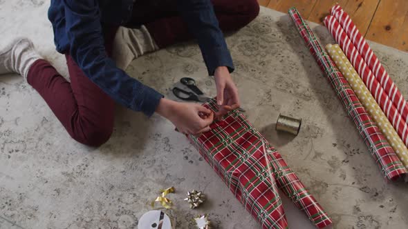 Mid section of woman wrapping Christmas presents at home