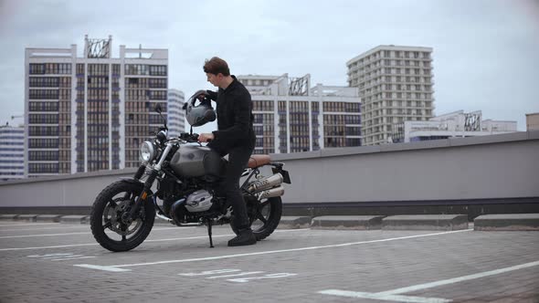 Man Coming to Motorbike and Wearing Helmet on Top of the Multilevel Parking