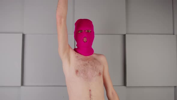 Unrecognizable Person in Pink Balaclava with a Bare Torso Makes Imaginary Gun Out of Hands and Makes