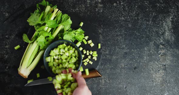 The Man's Hand Pours the Chopped Celery Into a Bowl