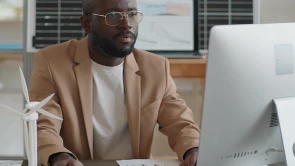 Afro-American Renewable Energy Engineer Working on Computer at Desk