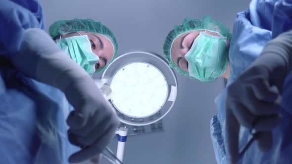 From Below Female Surgeons in Medical Uniform Using Professional Tools While Standing Under Bright