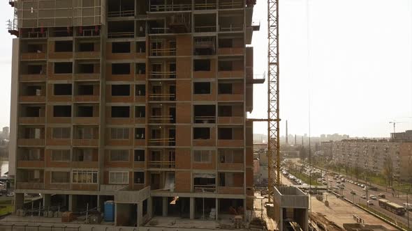 Raising the Camera Up Along a Building Under Construction with Empty Floor Spans and Workers on the