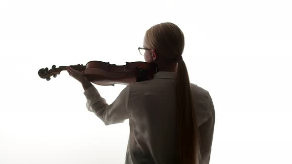 Woman Blonde Violinist in Glasses and a Blouse Begins to Play the Violin Standing with Back in a