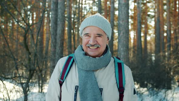 Slow Motion Portrait of Senior Man Smiling Looking at Camera in Winter Forest