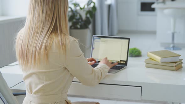 Young girl working at a laptop at home office. Young woman typing on laptop at the desk