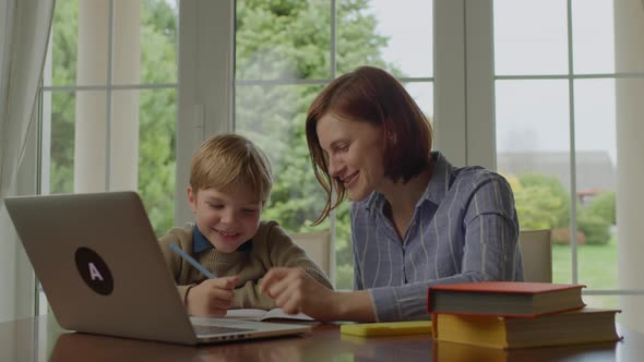 Young 30s Mother Making Online Homework with School Child at Home