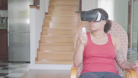 Pretty African American Woman Sitting on the Armchair at Home in the Virtual Reality Headset