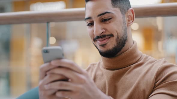 Closeup Young Arab Guy Holding Phone Looking at Screen Smartphone Smiling Receive Nice Email Message