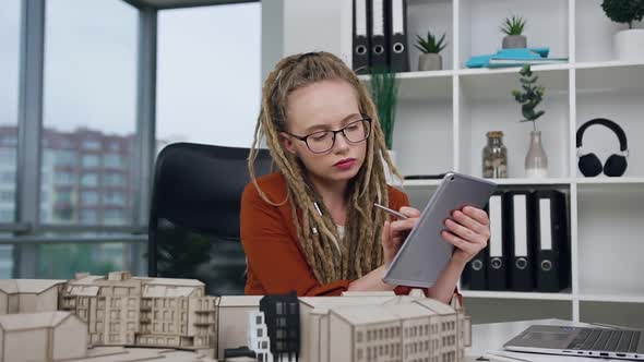 Female Architect with Dreadlocks Working with i-pad and Constructed Model