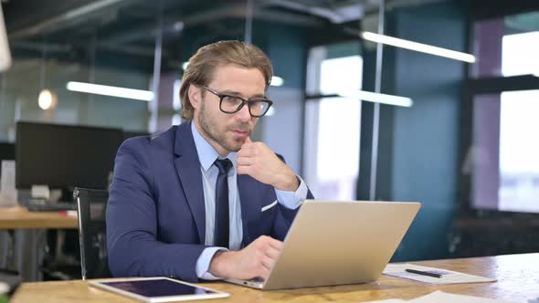 Pensive Businessman Thinking and Working on Laptop