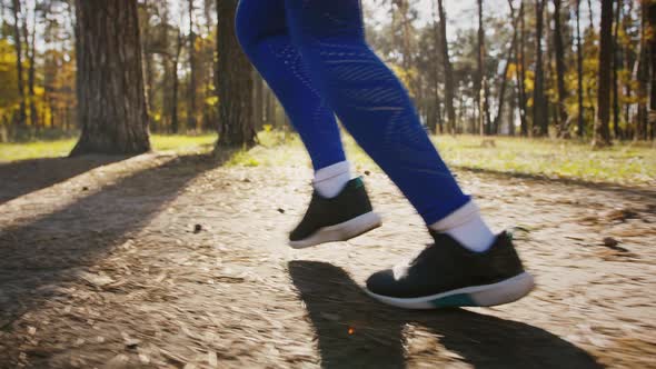 Legs of Unknown Young Woman Who Running By Path in Autumn Forest on Sunny Day