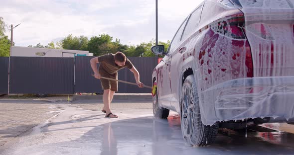 A Man Washes His Car During the Day Washes of the Foam