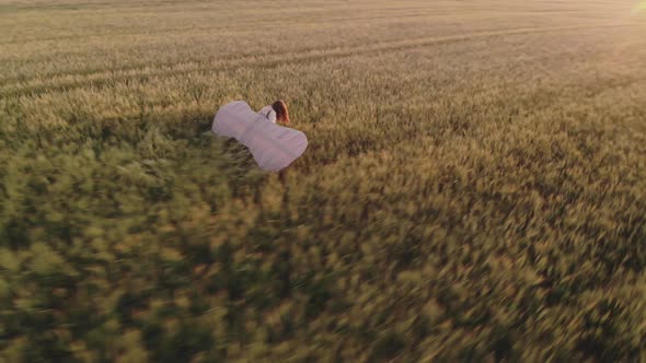 Lady Walks Along Field Holding Glider Wings in Evening