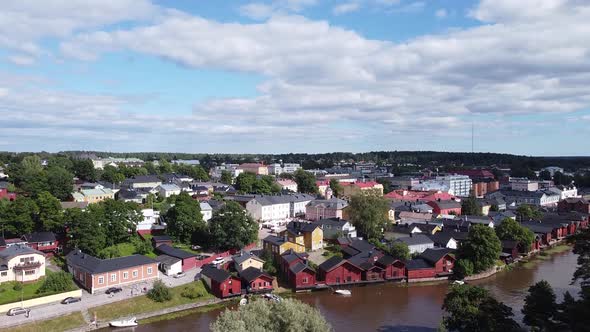 Aerial view showing red houses at river shore and cityscape with green trees in background. Porvoo,F