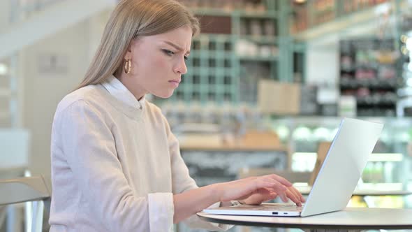 Young Woman Angry on Laptop in Cafe 