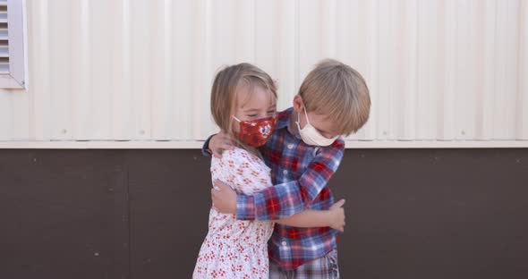 Two little kids hugging each other while wearing masks