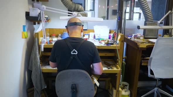 male jewelry maker hand polishing and buffing a silver ring in a jewellery making workshop.