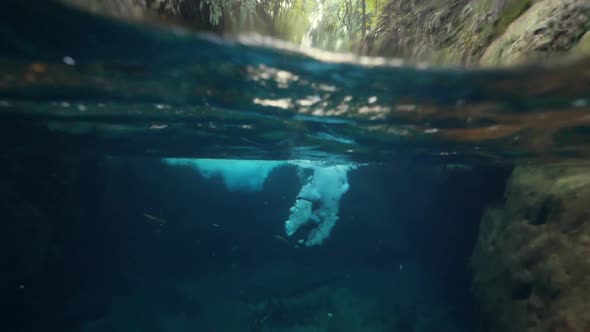 A Young Woman on Vacation Jumping Off to a Waterfall and Swimming Underwater