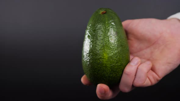 Avocado in a Hand of Woman Colored Background