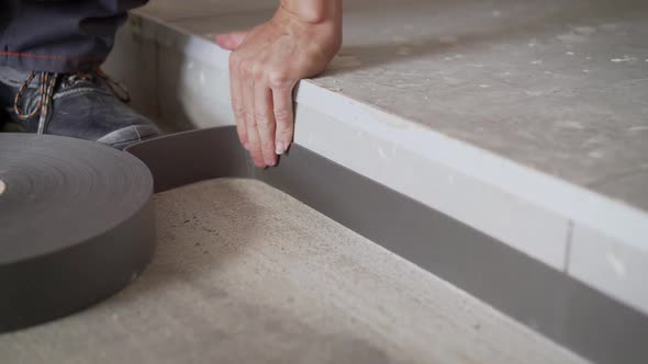 The Worker Glues the Floor Tape. Installation of Flooring. Damper Tape.