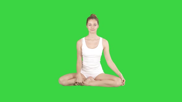 Cute Fitness Woman Exercising Yoga Sitting in Lotus Pose and Smiling After That on a Green Screen