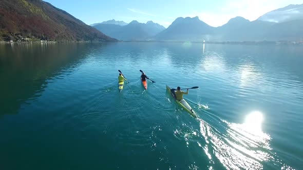 Three kayakers paddle in a scenic mountain lake