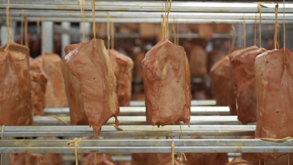 Sausage Production. Pieces of Ham Meat Hang on Strings Before Baking.