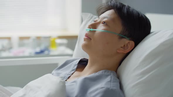 Sick Asian Woman Lying on Bed in Hospital Ward