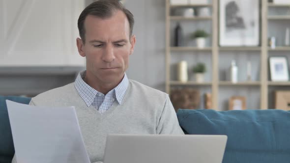 Middle Aged Man Doing Paperwork While Sitting in Creative Workspace