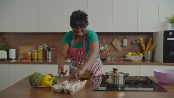 Elderly Black Woman Whisking Eggs in Bowl at Home