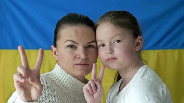 Young Woman with Her Daughter on the Background of the Flag of Ukraine