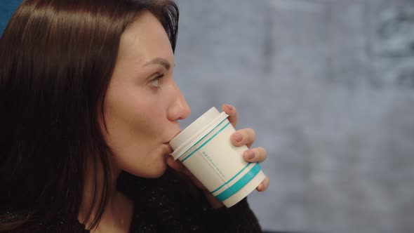 A Middleaged Woman Drinks Coffee and Dreamily Looks Out of the Train Window Enjoying the Winter