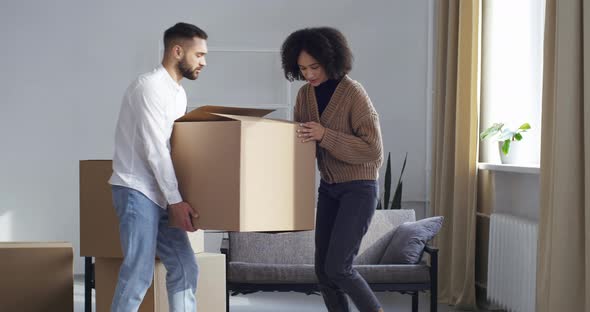 Multiethnic Couple Curly Haired Afro Woman and Caucasian Man Carrying Large Cardboard Box Parcel To