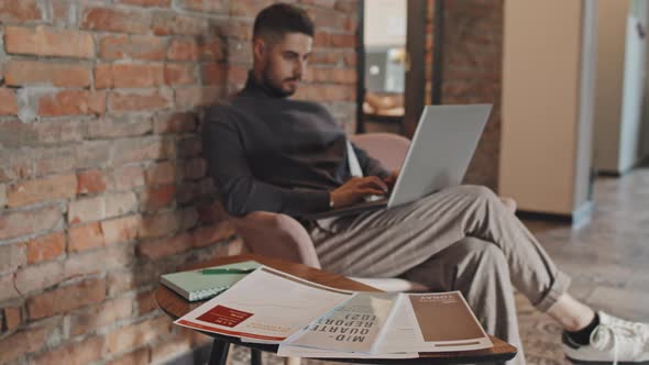 Man Preparing Mid-Quarter Report on Laptop