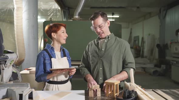 Man and Woman Joiners Using Digital Tablet While Working in Workshop