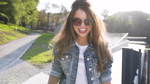 Smiling Funny Woman while Walking in Park in Summer Dressed in Blue Jeans Jacket