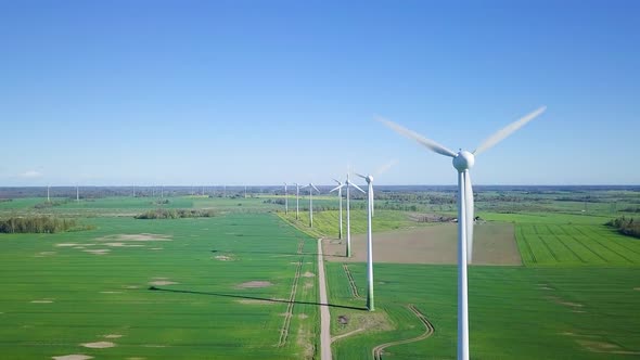 Aerial view of wind turbines generating renewable energy in the wind farm, sunny spring day, low fly