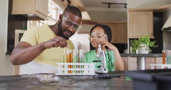 Focused african american father and daughter doing science experiments at home