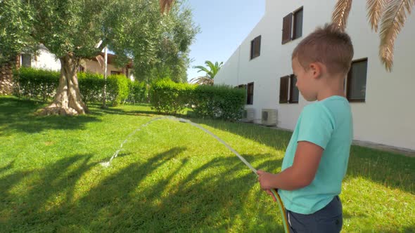 Child Taking Part in Household Duties and Watering Green Lawn By the House