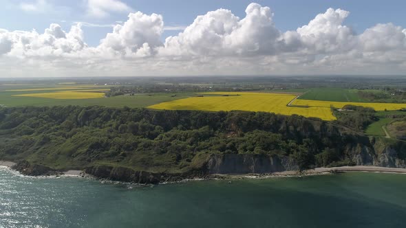 Panoramic drone view of Longues sur Mer sea cliff on sunny day. Aerial flying backwards