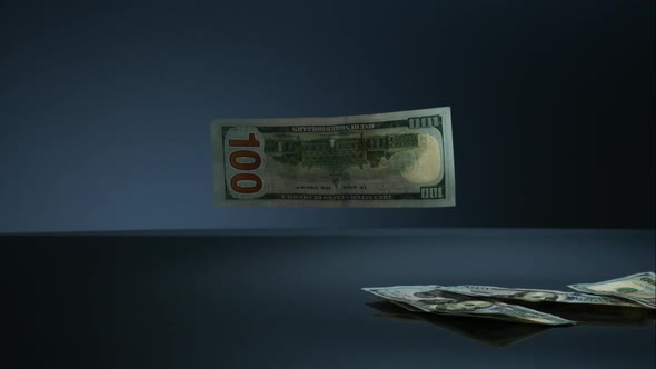 American $100 Bills Falling onto a Reflective Surface