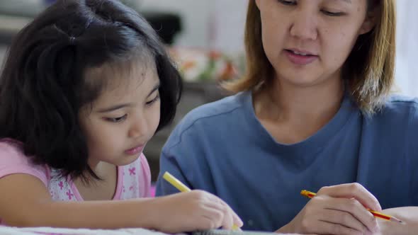 Close up shot Little Asian girl with mother doing homework in the bed room