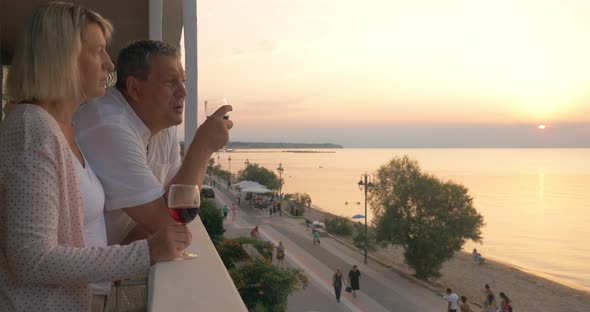 Couple drinking wine and looking at resort from balcony